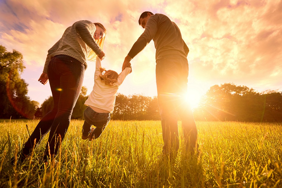 Couple lifting up their child in front of the sunset