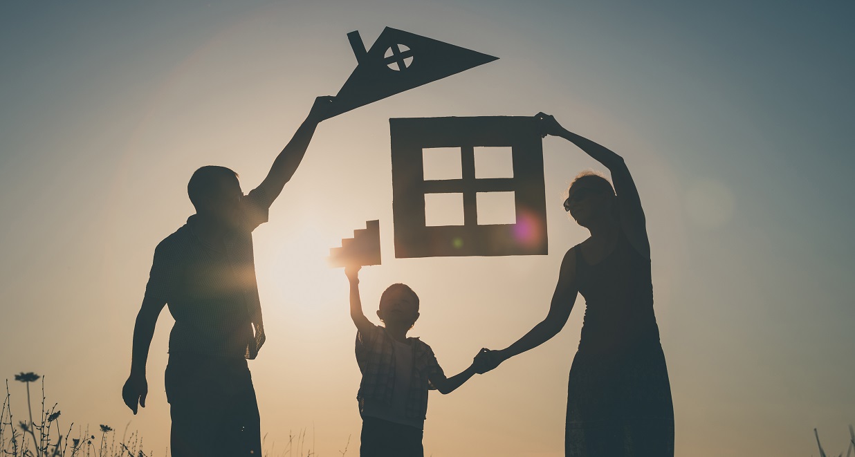 Family holding a cut out of a house