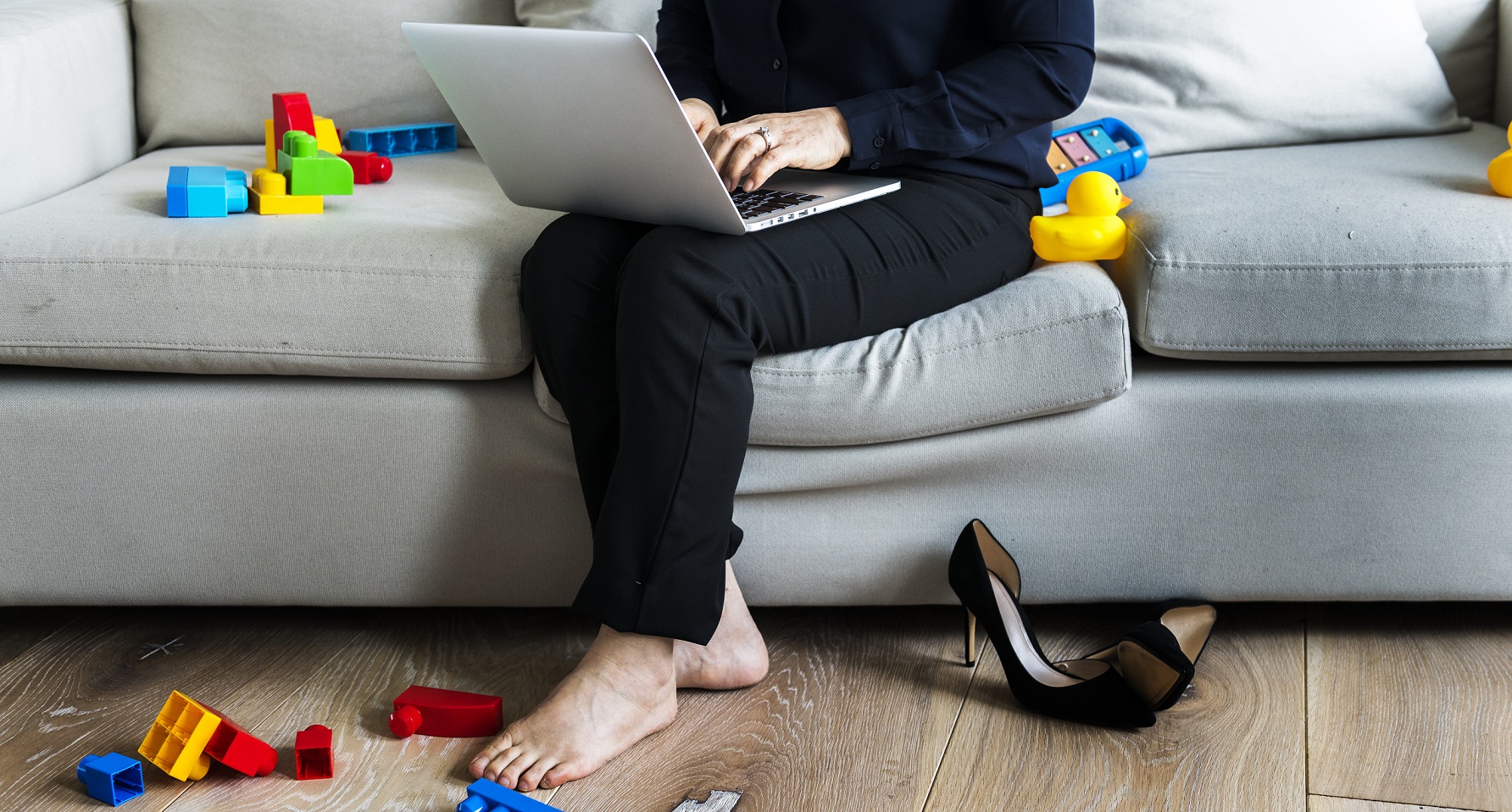 woman working on a laptop with toys on the ground