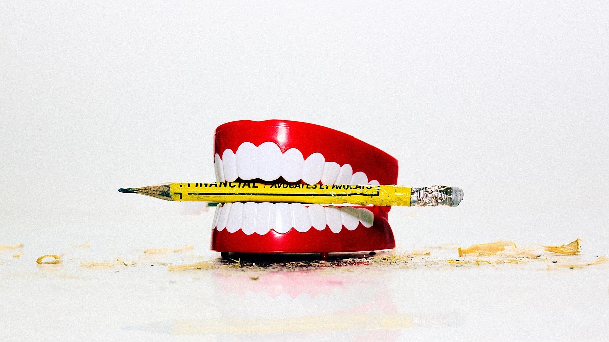 Dentures holding a yellow crayon between teeth