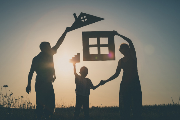 Family holding a cut out of a house