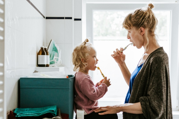 Woman and daughter brushing teeth